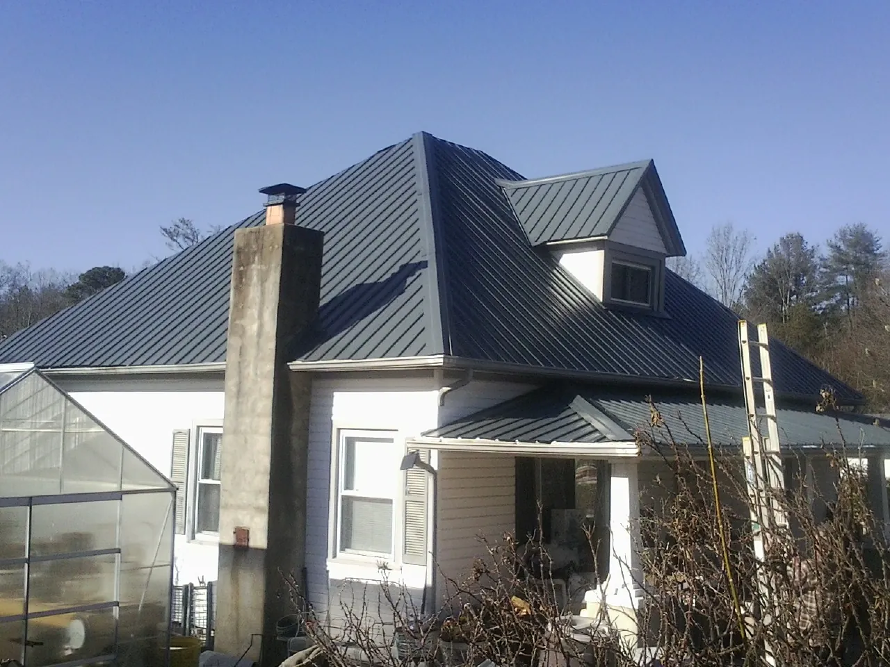 Dark blue standing seam metal roof on a white farmhouse with dormer — Slate & Tile Roof Repair by Roofing Brothers in Onemo