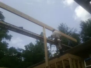 Carpenter setting a ridge beam over a new addition frame — Ice Dam Removal by Roofing Brothers in Onemo