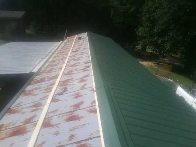 Old rusted panels beside newly installed green metal roofing — Wind Damage Roof Repair by Roofing Brothers in Onemo