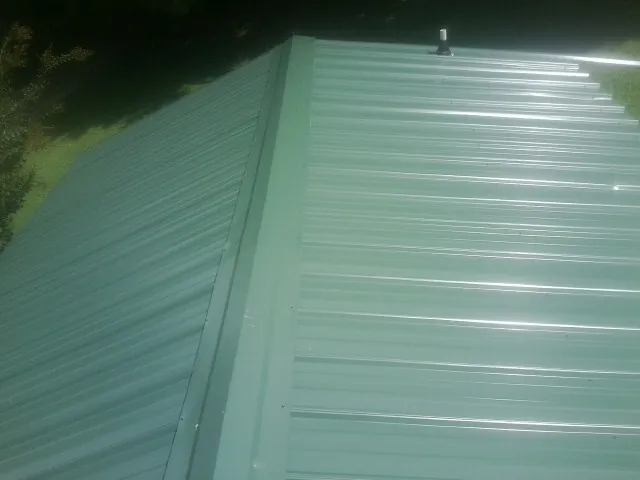 New green metal panels meeting at the ridge of a roof — Flat Roof Repair work by our crew in Onemo