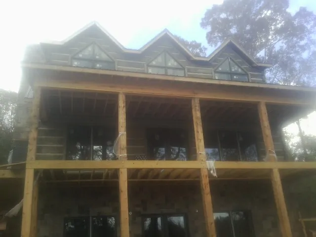 Dormers and porch framing on a large log home under construction — Roof Coating work by our crew in Onemo