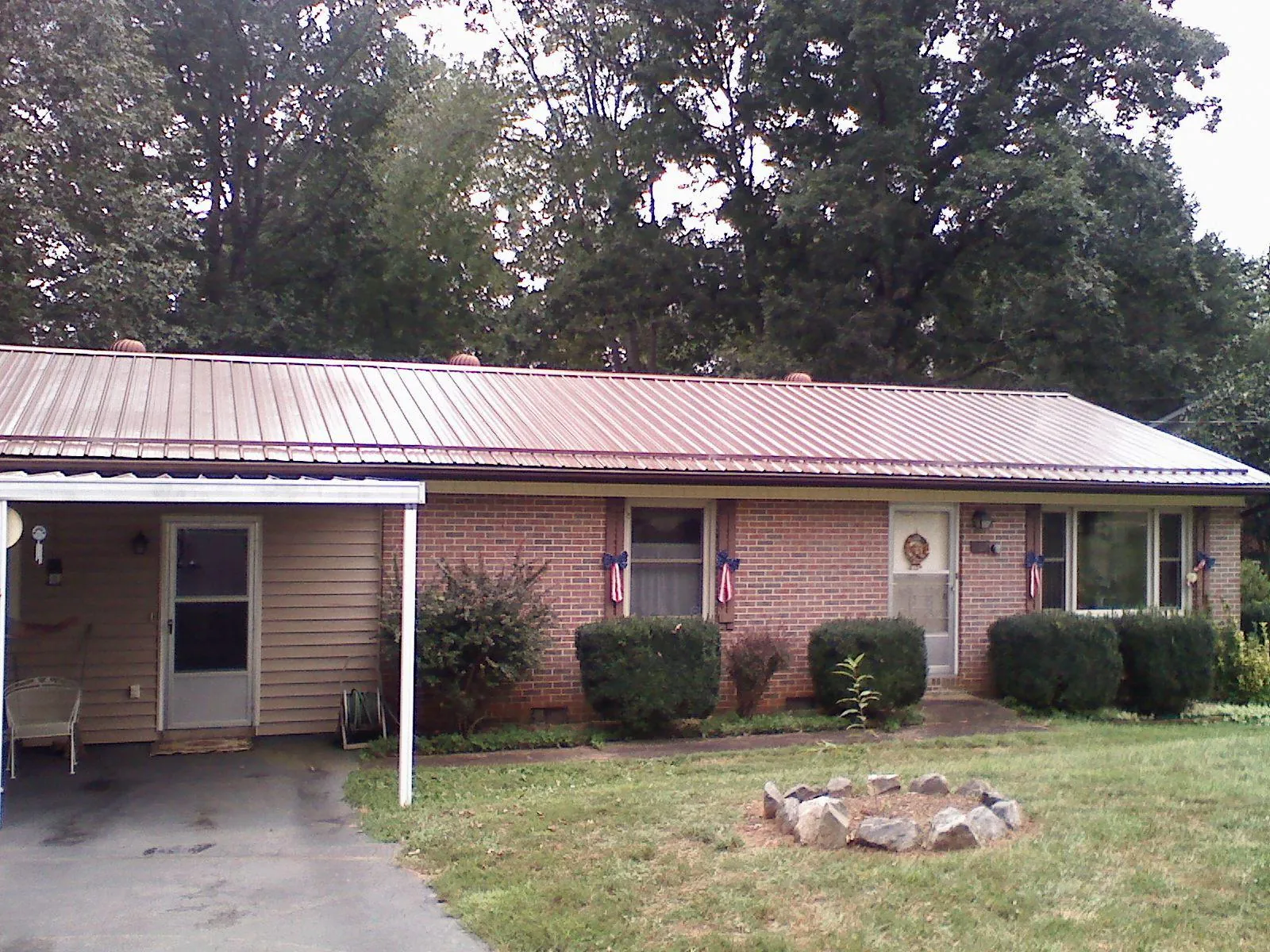 Bronze metal roof and carport on a brick ranch home — Roof Repair work by our crew in Onemo